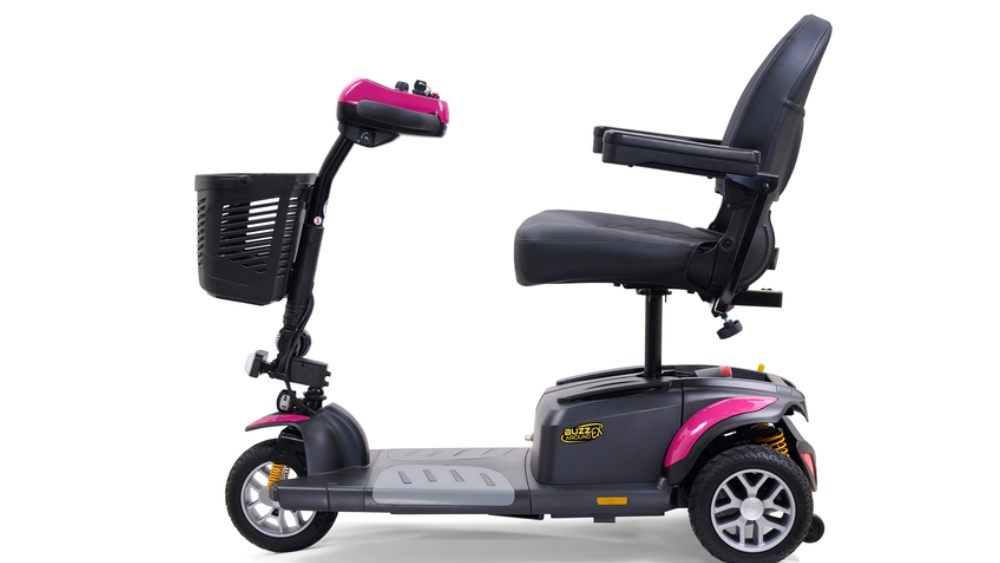 The BuzzAround EX 3-Wheel Scooter is a three-wheeled electric mobility scooter featuring a black seat with armrests, a front basket, and stylish pink accents on the handles and wheel covers.