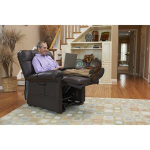 A man relaxes with his feet up in a Cloud Lift Chair w/ MaxiComfort, using a laptop in a living room featuring hardwood floors, a rug, and a staircase in the background.