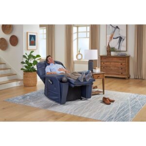A man reclines with his feet elevated in the Cloud Supreme with Twilight Lift Chair, set in a bright living room featuring wooden furniture, a rug, and decorative items.