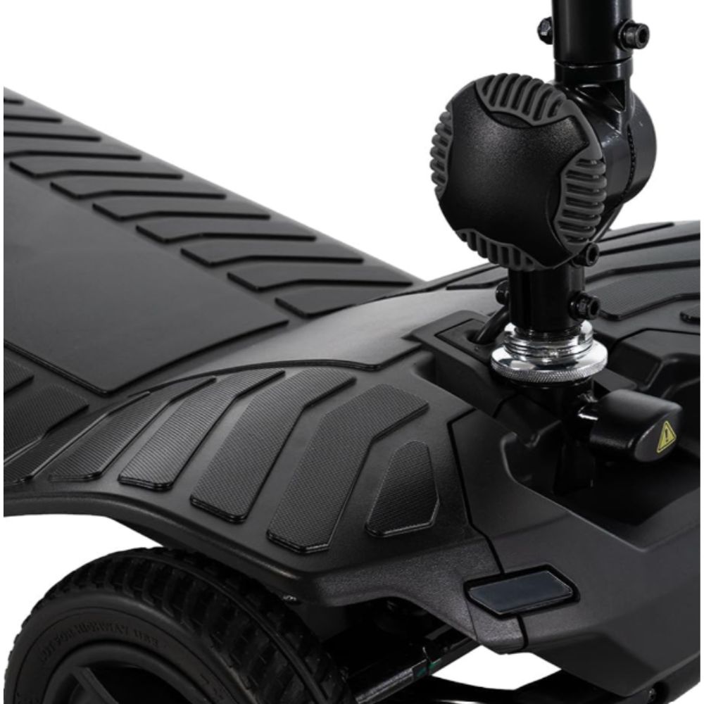 Close-up of the Pride Go Go Ultra X 4-Wheel Gen 3 scooter’s black deck and steering column, highlighting the textured footrest area, part of a wheel, and a circular component mounted near the handlebar stem.