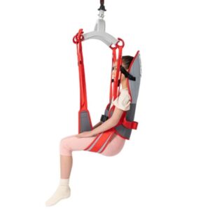 A woman sits upright in a Molift RgoSling Toilet HighBack patient lift sling, suspended from a mechanical lift, wearing light clothing and socks.
