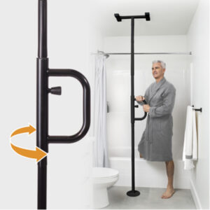 A man in a gray robe holds the Security Pole, featuring a rotating handle, which is installed as a floor-to-ceiling support beside a bathtub in a white bathroom.