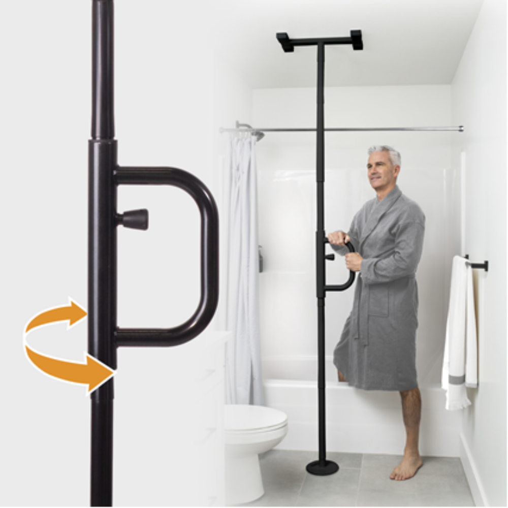 A man in a gray robe holds the Security Pole, featuring a rotating handle, which is installed as a floor-to-ceiling support beside a bathtub in a white bathroom.