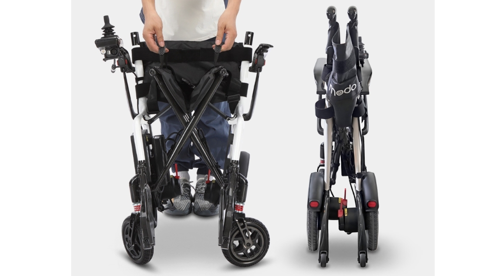 A person stands behind a folded Modo Breeze electric wheelchair, shown from the front and back, demonstrating its compact storage design.