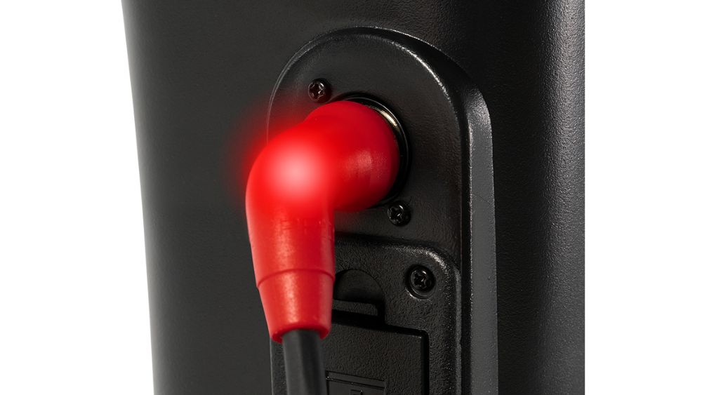 A close-up of a red power cable plugged into the back of a black Victory Platinum 4-Wheel Scooter, with a glowing red light at the connection point.
