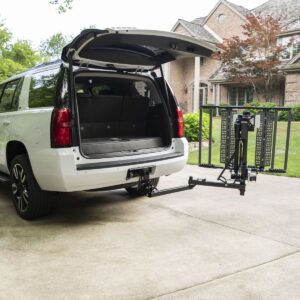 A white SUV with its rear hatch open is parked in a driveway. A Bruno Out-Sider® (ASL-275) scooter lift is securely attached to the hitch, ensuring convenient scooter transport.