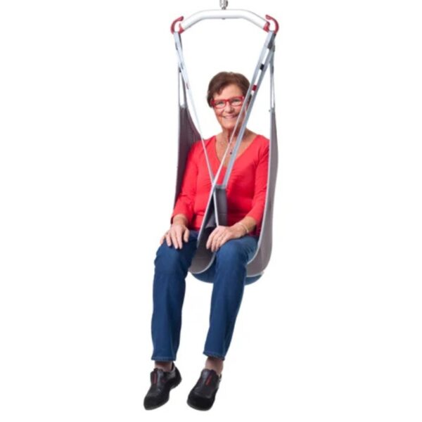 An adult wearing a red shirt and blue pants is comfortably seated in a Molift EvoSling MediumBack Net Padded, securely supported by a harness attached to its sturdy metal frame.