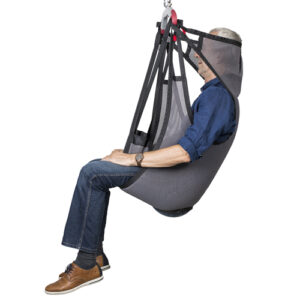 A man in a blue shirt and jeans is seated in a Molift EvoSling Shadow highback safety harness lift.
