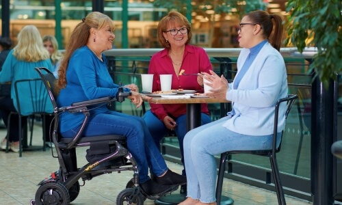 person in wheelchair eating and talking with friends