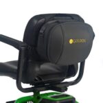 Close-up of a black scooter seat with a Golden Tech Universal Travel Case on the backrest. The scooter is partially visible, featuring a green base and armrest.